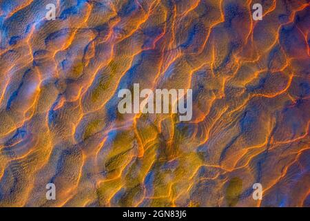 Clear golden water stream pattern with sand waves under it Stock Photo