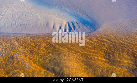 Clear golden water stream pattern with sand waves under it Stock Photo