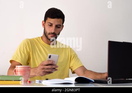 Young happy businessman smiling while reading his smartphone. concentrated student looking for information on his phone. concept of working at home Stock Photo