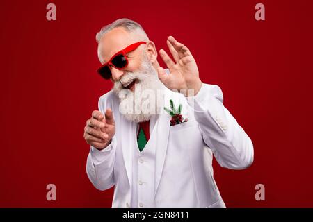 Photo of happy funky positive old man wear sunglass dance christmas showman isolated on red color background Stock Photo