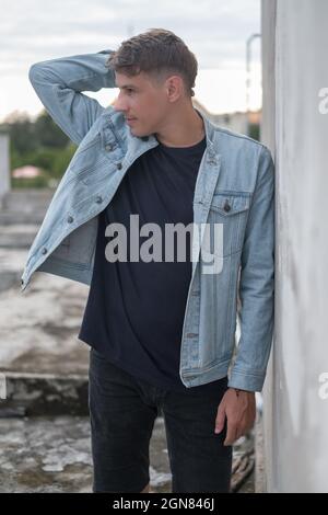 Portrait of young handsome Caucasian man in casual wearing and denim jacket, looking aside. Holding his head with his hand, Pensive look. High quality Stock Photo