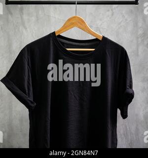 Young male in front blank black t-shirt Roll up sleeves template, Three color black white gray hang on cement background for your design mockup concep Stock Photo