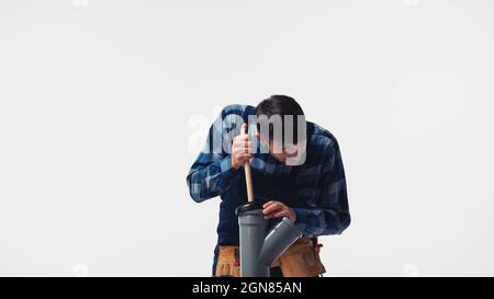 Plumber cleaning plastic pipe with plunger isolated on white Stock Photo