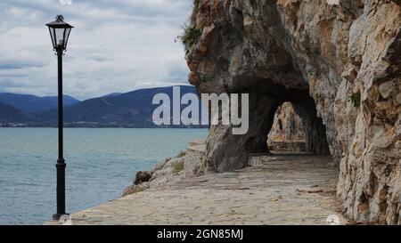 a traditional street light on the coastal sidewalk next to the caves of Akronafplia by the sea, Nafplio, Peloponnese, Greece Stock Photo