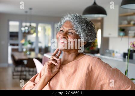 Happy african american senior woman touching face, standing standing in kitchen Stock Photo