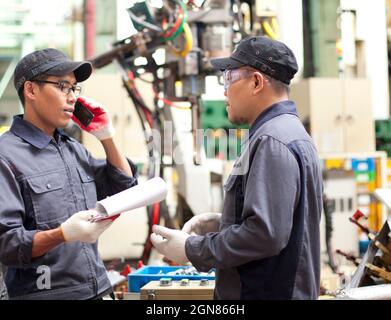 Two technician in a factory talking how repair a robot machine Stock Photo