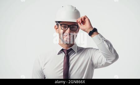 Positive architect in eyeglasses holding protective helmet isolated on white Stock Photo