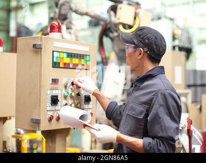 Manufacturing worker operating a robot machine with a control panel Stock Photo