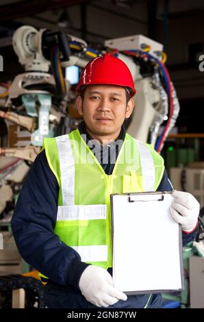 Engineer  holding a notepad with robot machine on the bacground Stock Photo