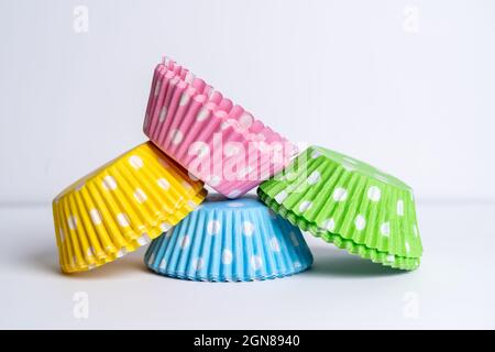 four packs of brightly colored grease proof paper cup( fairy) cake cases for presentation at parties  and events after baking in the oven pink, green, Stock Photo