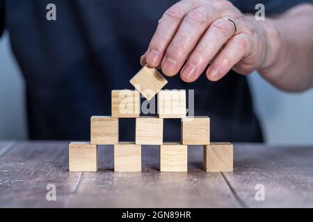 template mock up of ten timber block cubes with a man holding  the top centre one pivoted to form a diamond Stock Photo