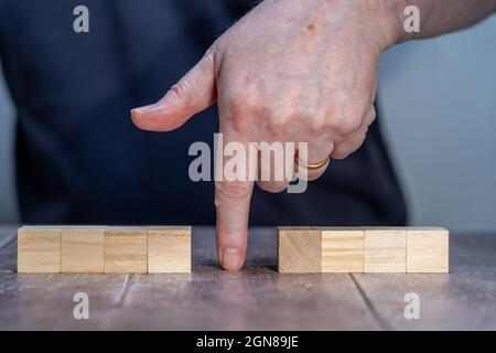 blank template mock up of two sets of four timber block cubes , with a man in the background pointing between the blocks Stock Photo