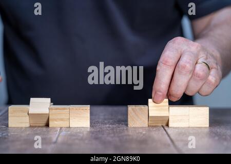 blank template mock up of two sets of four timber block cubes , centre ones pivoted with a man in the background holding the centre block Stock Photo