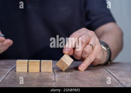 A mock up of Four blank timber block cubes three in a block with a man holding the end cube forming a multi faceted diamond shape Stock Photo