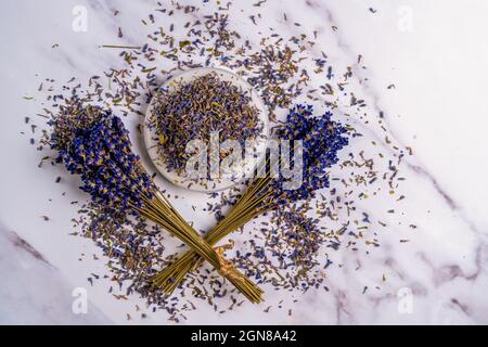 Still life Aromatherapy Dried Lavender bunches , flowers and scattered petals and stamens on a dish on a marble background Stock Photo