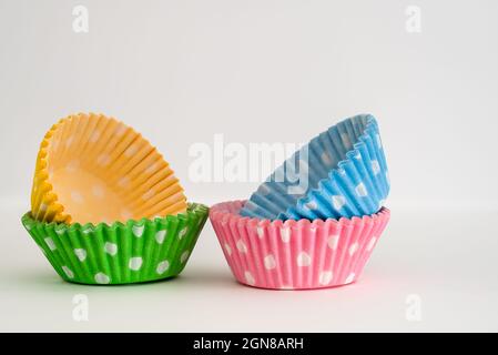 four packs of brightly colored grease proof paper cup( fairy) cake cases for presentation at parties  and events after baking in the oven Stock Photo