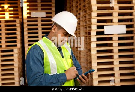 worker using smartphone in warehouse pallet Stock Photo