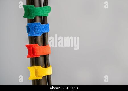 four multicolored hook and loop fabric cable ties connecting power cables together on a plain grey background Stock Photo