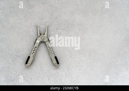 Multi tool stainless steel on a plain brushed concrete background top view flat lay of oak Stock Photo