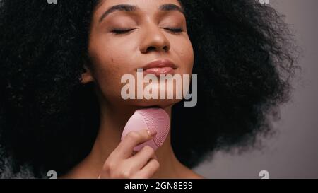 african american woman using silicone cleanser on neck isolated on grey Stock Photo