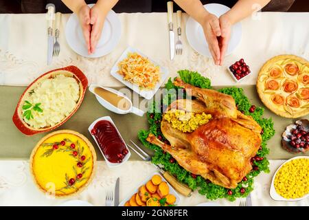 Family holding hands over table setting and praying. Thanksgiving Day. Stock Photo