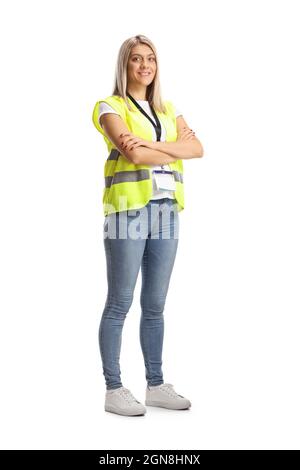 Full length portrait of a female security officer in a safety vest standing with crossed arms isolated on white background Stock Photo