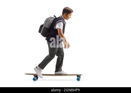 Full length profile shot of a schoolboy in a uniform riding a skateboard isolated on white background Stock Photo