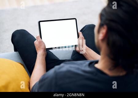 Young man holding digital tablet while sitting on sofa Stock Photo