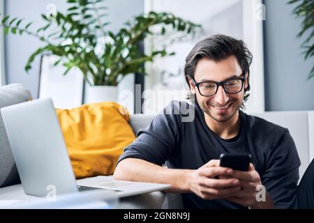 Male freelance worker using smart phone while working at home Stock Photo