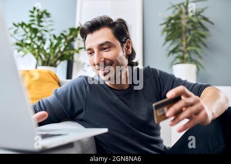 Man with credit card using laptop at home Stock Photo