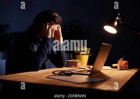 Tired businessman sitting at desk while working late night at home Stock Photo