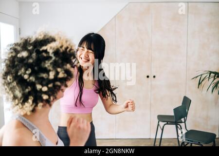 Smiling woman practicing zumba with friend at home Stock Photo