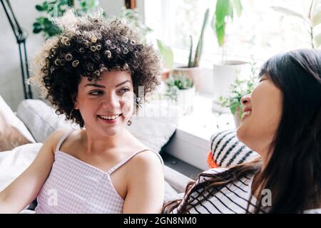 Smiling young female friends looking at each other while talking Stock Photo