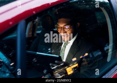 Smiling businessman using digital tablet while sitting in car Stock Photo