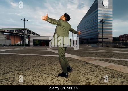 Businessman with arms outstretched spinning on footpath Stock Photo