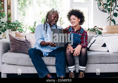 Smiling father and daughter video calling through digital tablet in living room Stock Photo