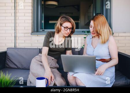 Female professionals using laptop while sitting on sofa Stock Photo
