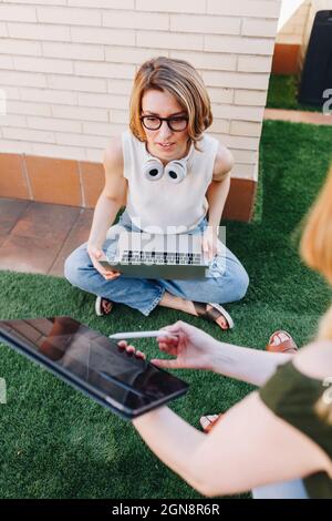 Businesswoman explaining colleague over digital tablet while working at terrace Stock Photo