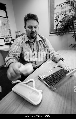 JOHANNESBURG, SOUTH AFRICA - Aug 09, 2021: An Angry man frustrated with a broken laptop computer in grayscale Stock Photo