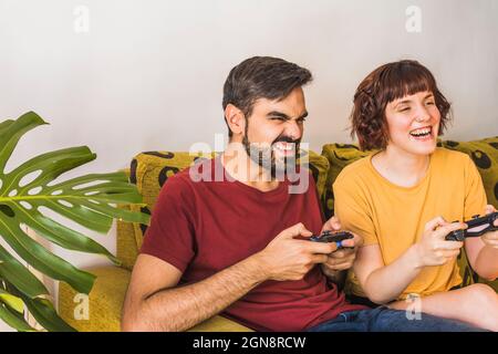 Man beating woman at video games with controller on console over blue  background. Boyfriend celebrating win and girlfriend feeling disappointed  about losing online gameplay in studio Stock Photo - Alamy