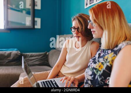 Businesswomen using laptop while sitting on sofa at home Stock Photo