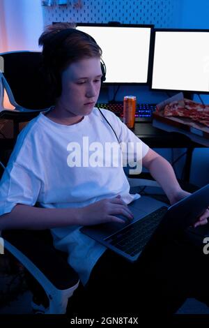 Gamer boy using laptop while sitting on chair at home Stock Photo