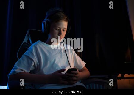 Boy using smart phone while wearing headphones at home Stock Photo