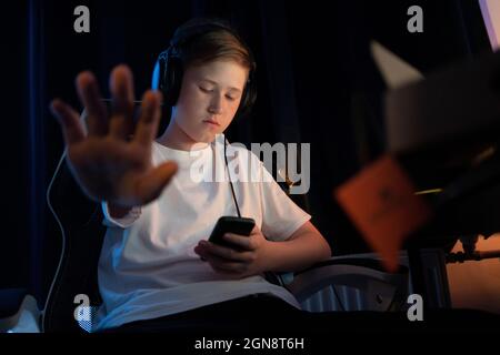 Boy showing stop sign while using smart phone at home Stock Photo