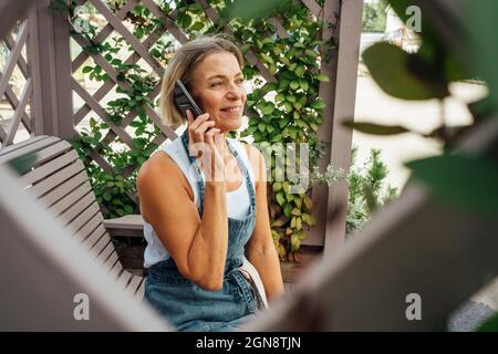 Female farmer talking on mobile phone at plant nursery Stock Photo