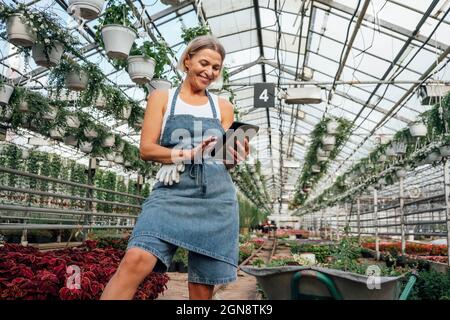Smiling female agriculture worker using digital tablet at plant nursery Stock Photo