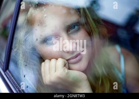Girl day dreaming while looking through car window Stock Photo