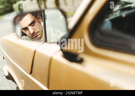 Reflection of serious man on side-view mirror of car Stock Photo