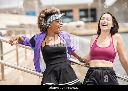 Mid adult women laughing while standing in front of railing Stock Photo