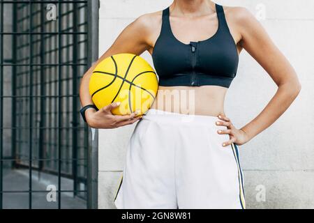 Basketball player with sports ball and hand on hip Stock Photo